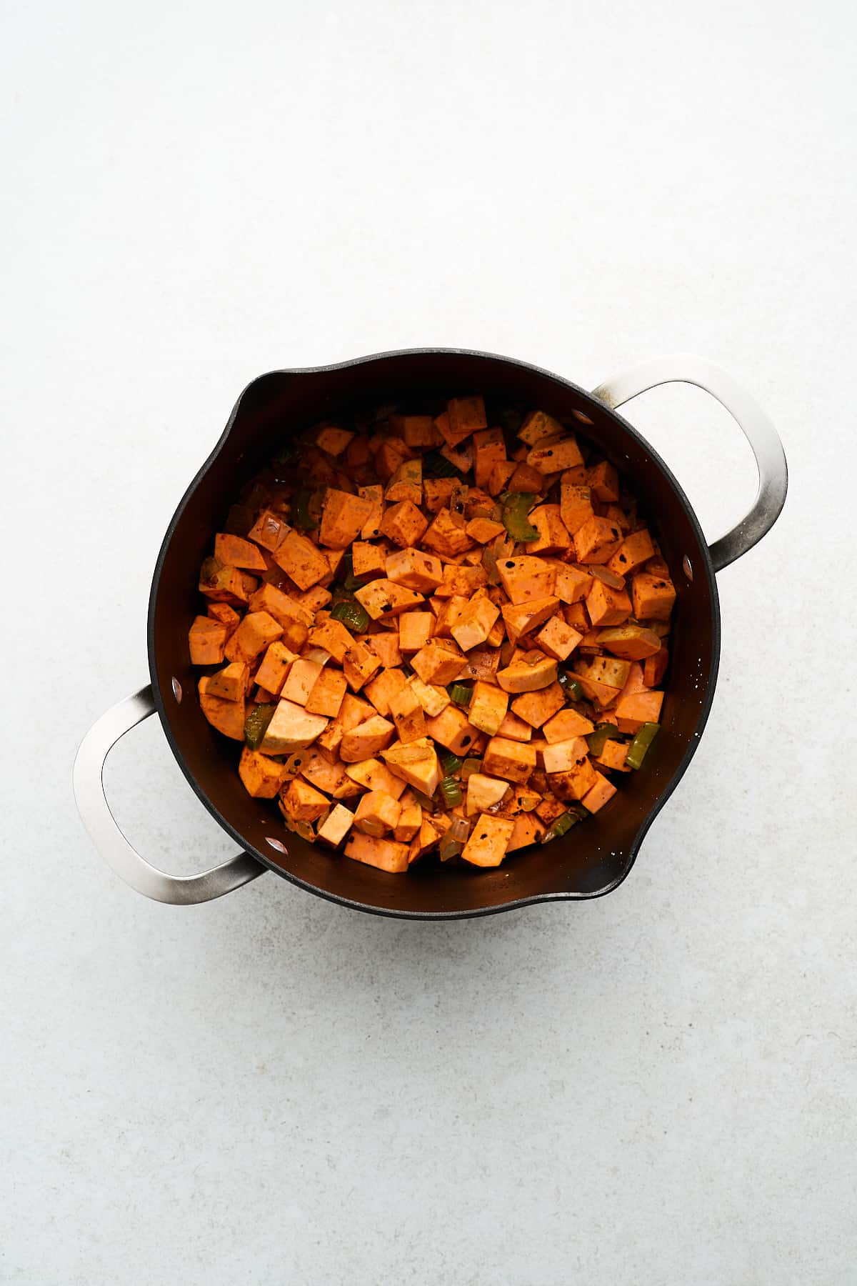 Sweet potatoes, spices, and vegetables in a pot.