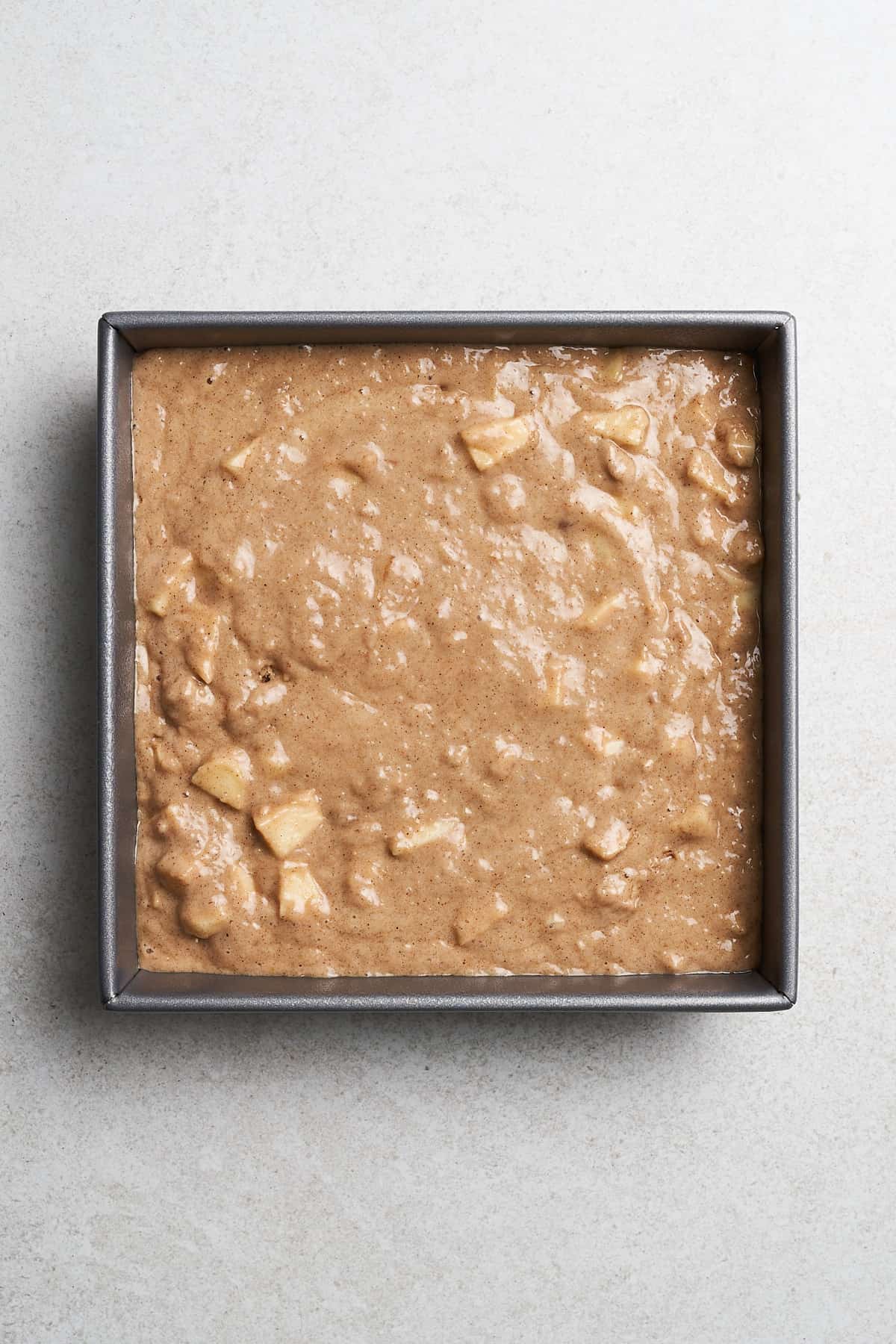 Vegan apple cake batter in a pan.