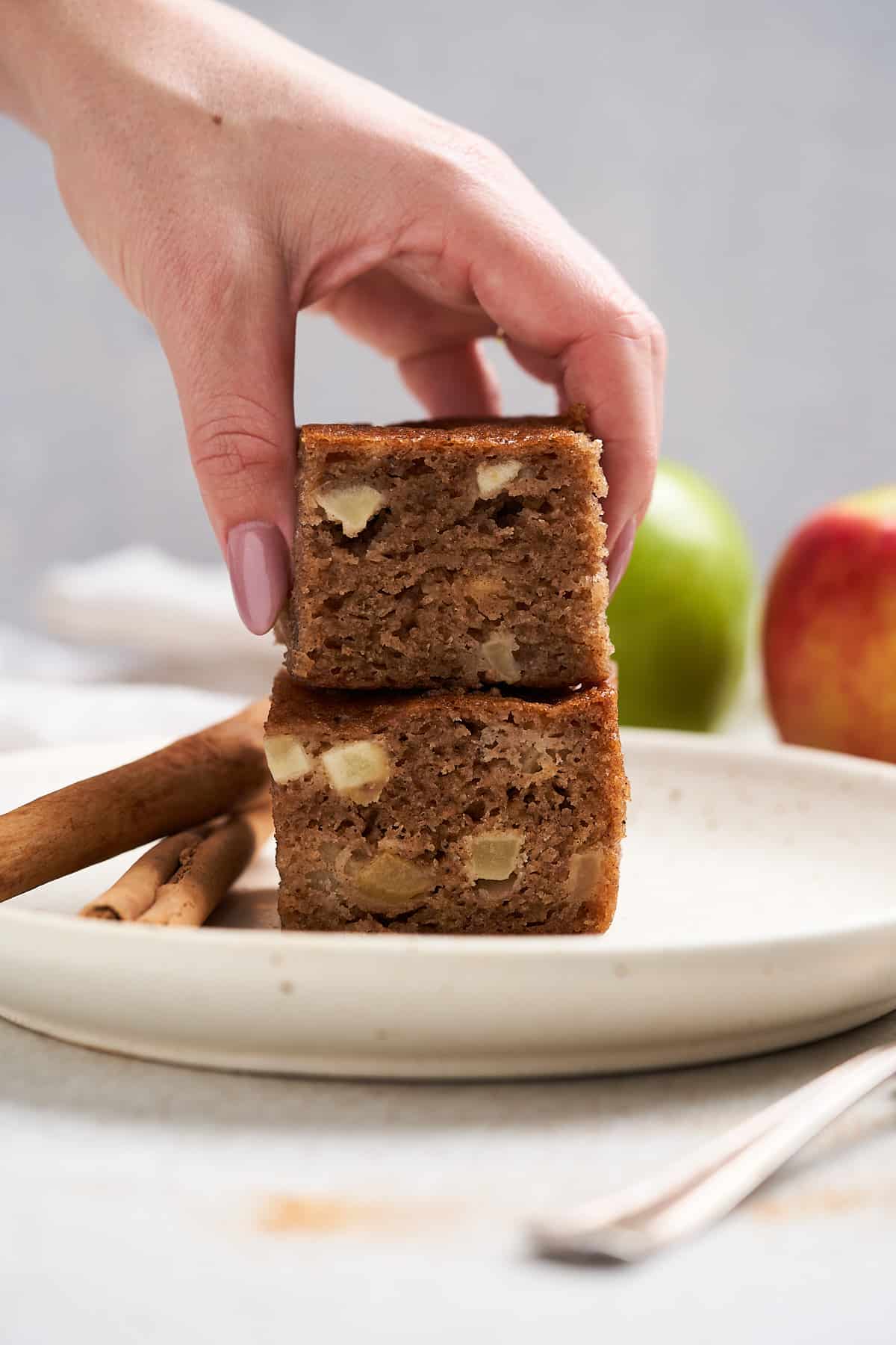 Hand putting down a slice of vegan apple cake.