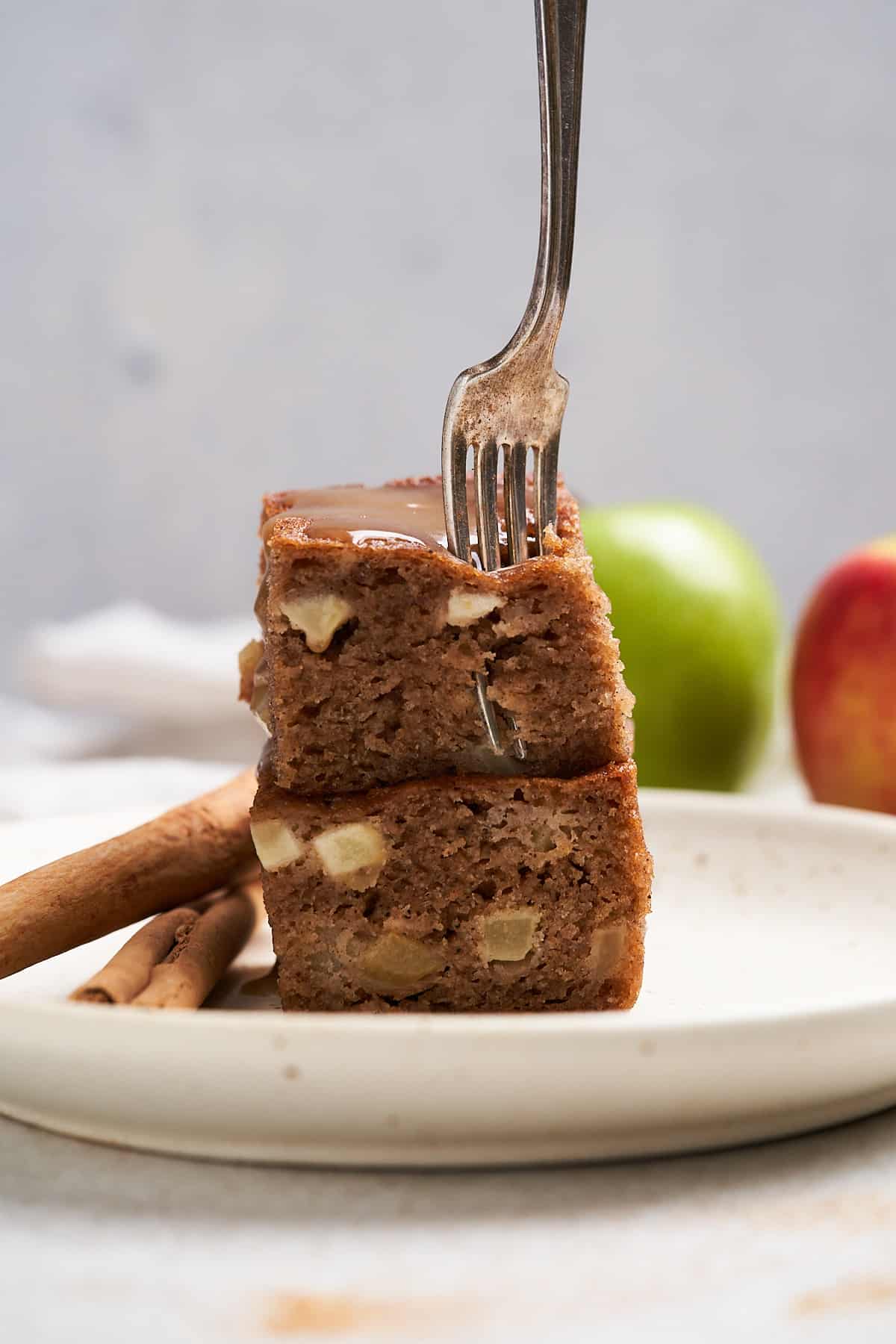 Fork breaking off a piece of vegan apple cake.