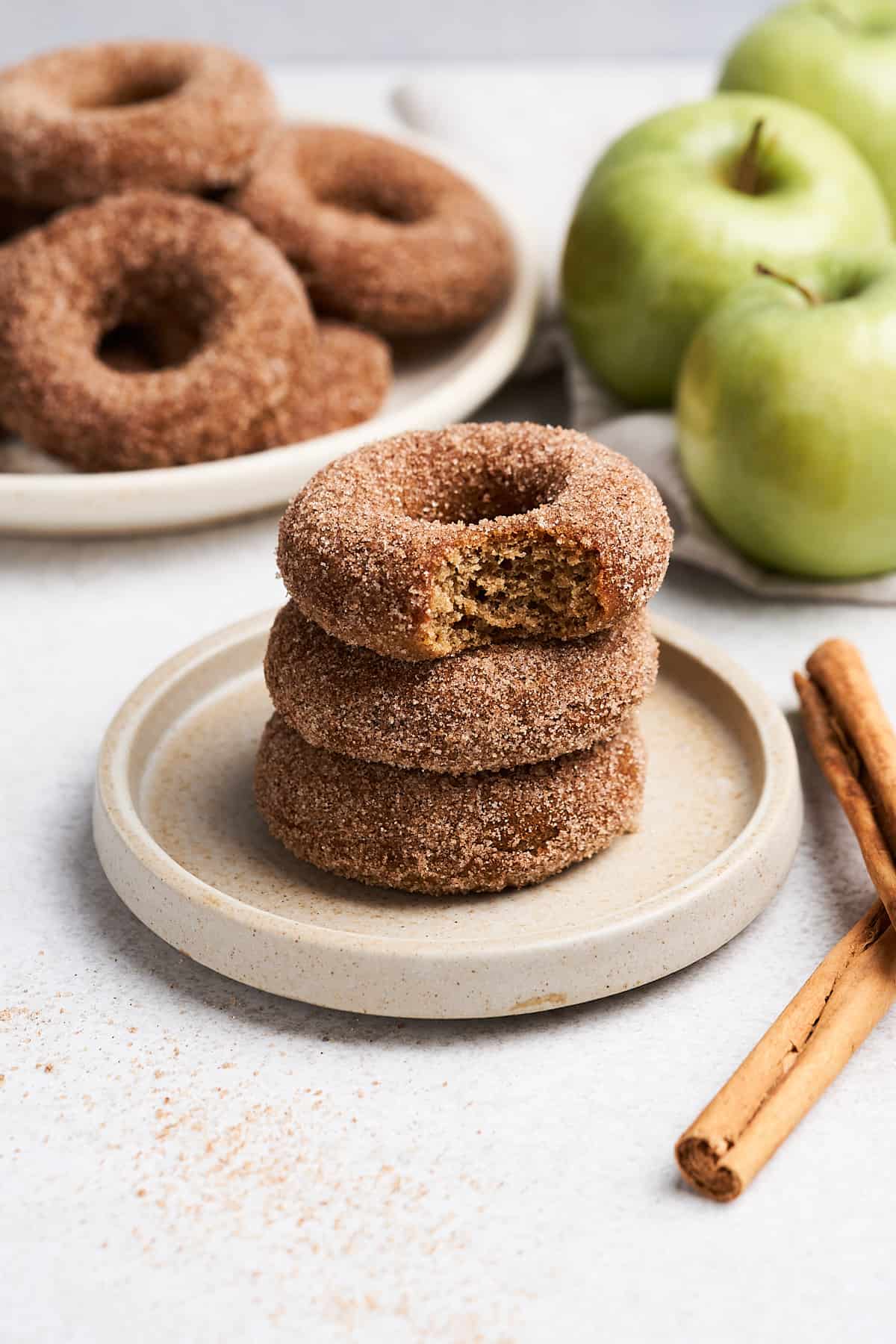 Vegan apple cider donuts stacked on a plate.