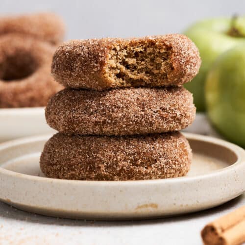 Vegan apple cider donuts stacked on a plate.