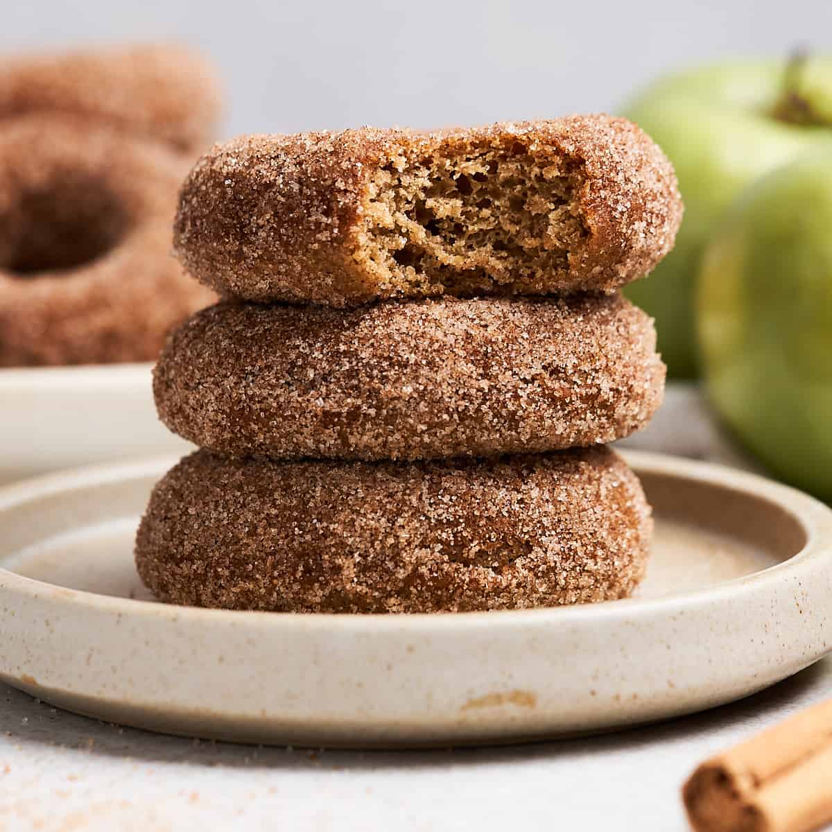 Vegan apple cider donuts stacked on a plate.