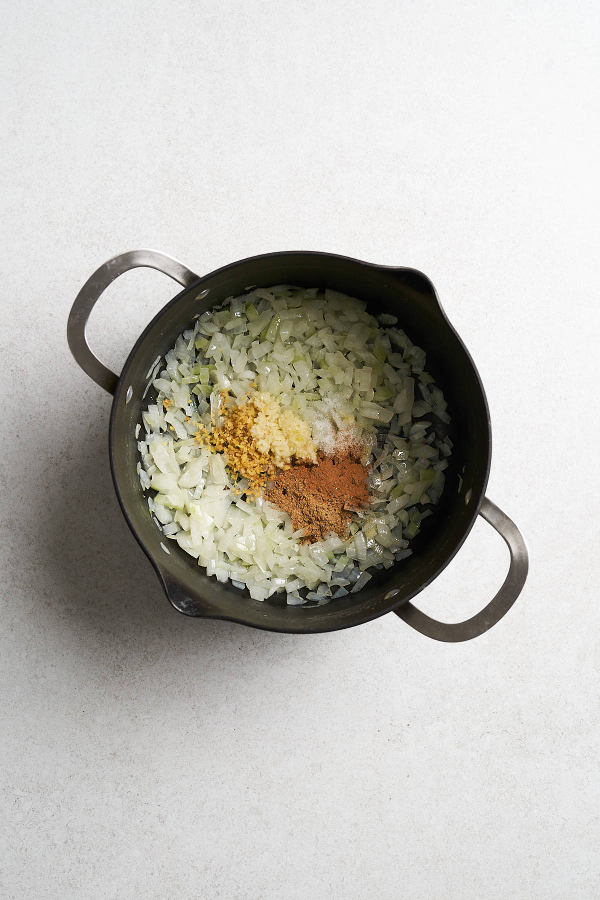 Sautรฉed onions and aromatics in a pot.