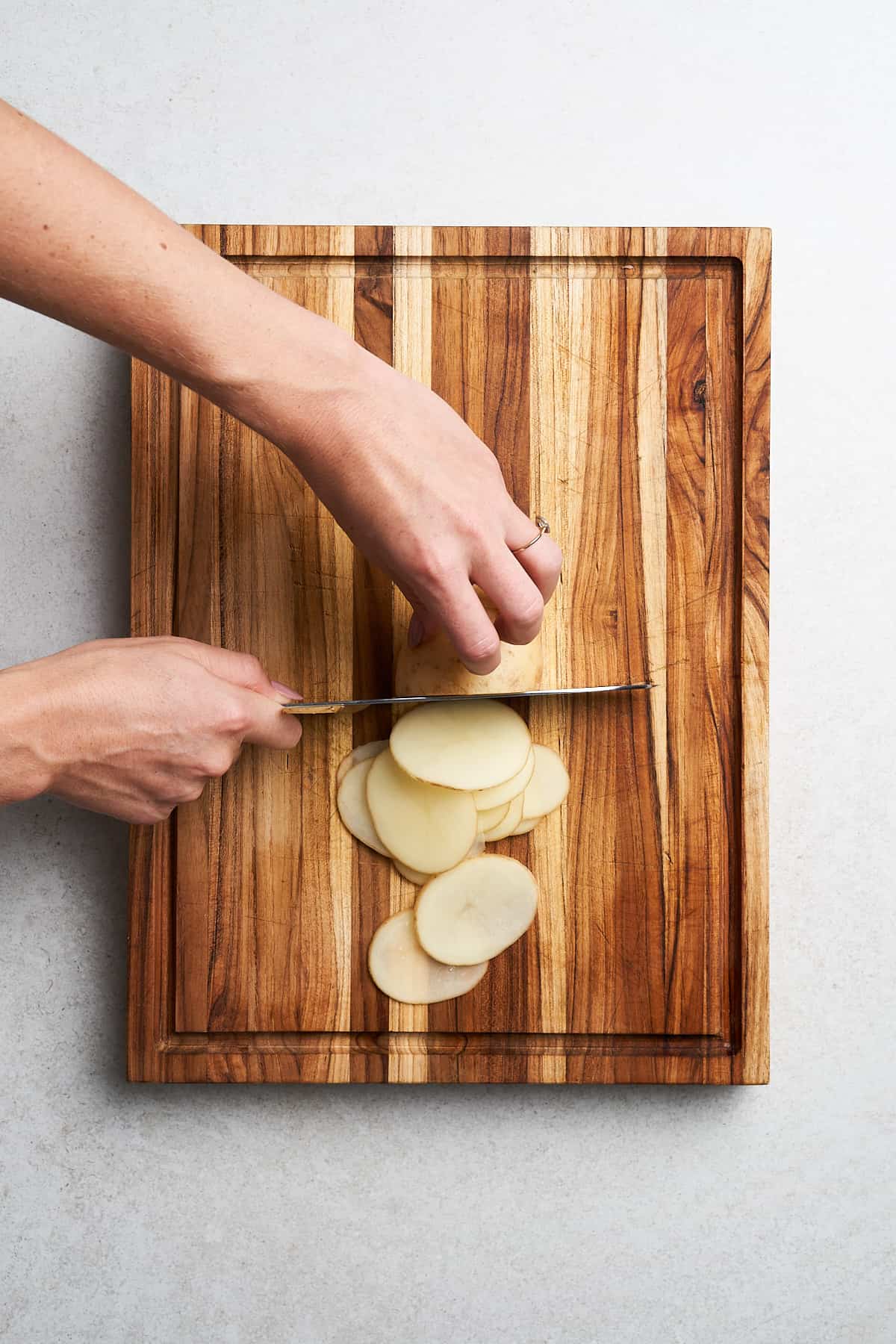 Slicing potatoes thinly.