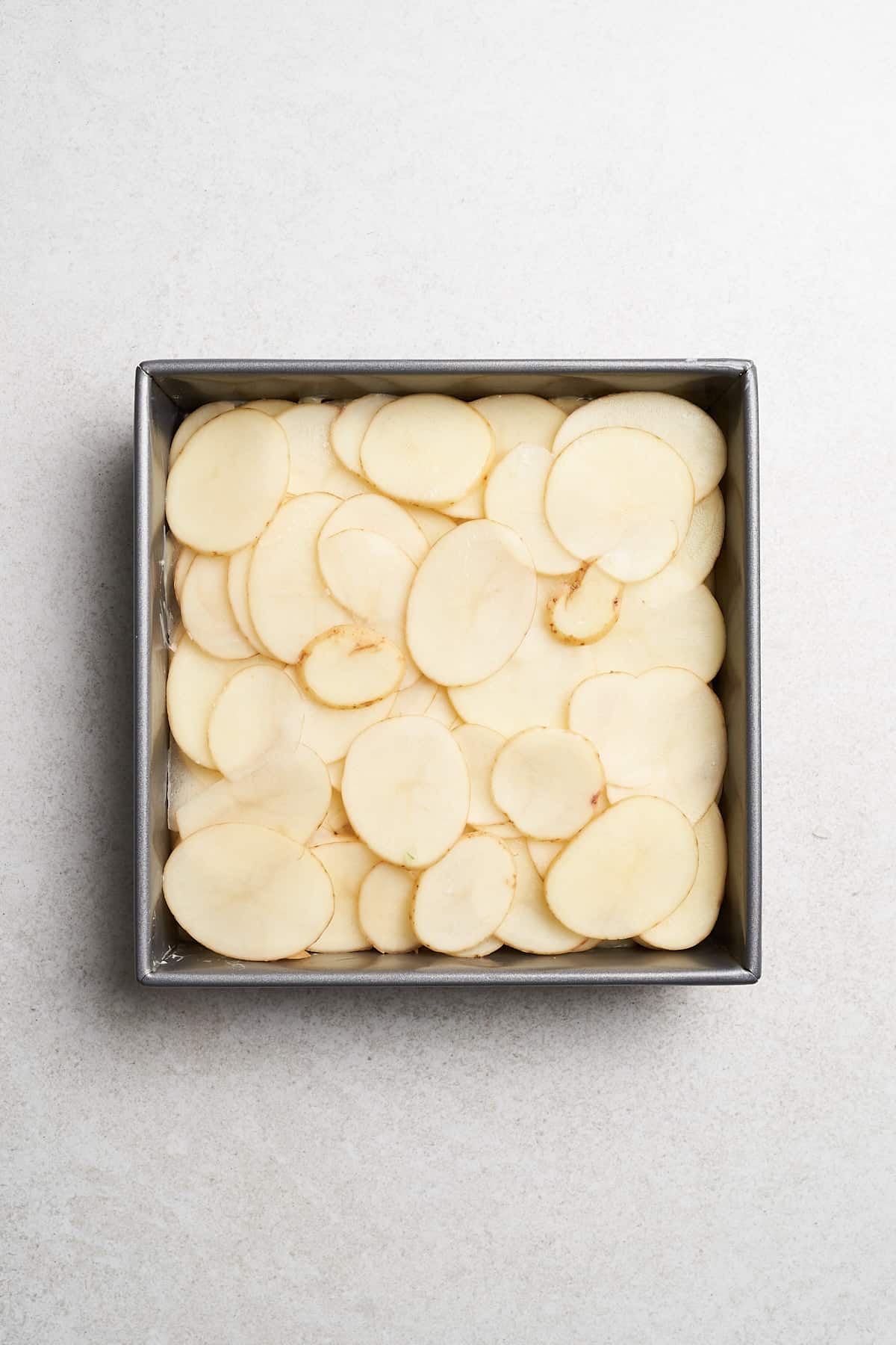 A layer of sliced potatoes in a baking pan.