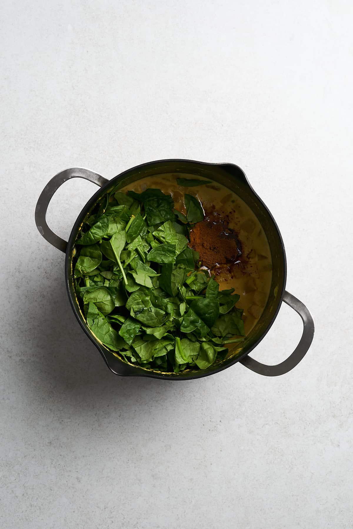 Butternut squash curry and baby spinach in a saucepan.