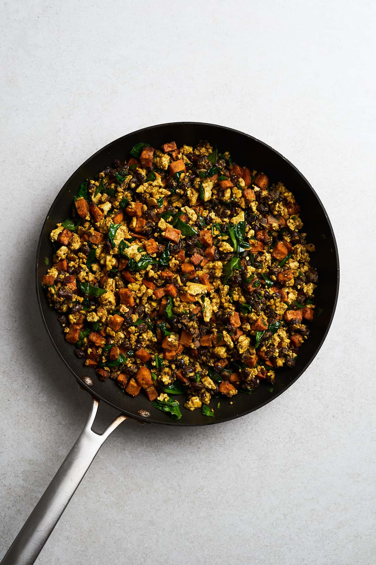 Tofu with spinach and seasonings in a frying pan.
