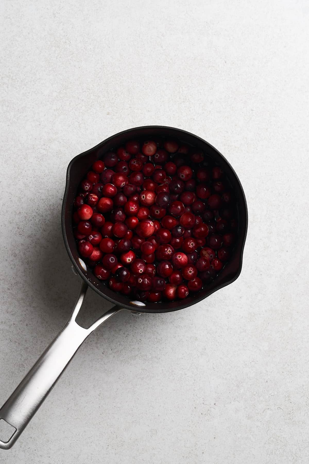 Uncooked cranberries in a saucepan.