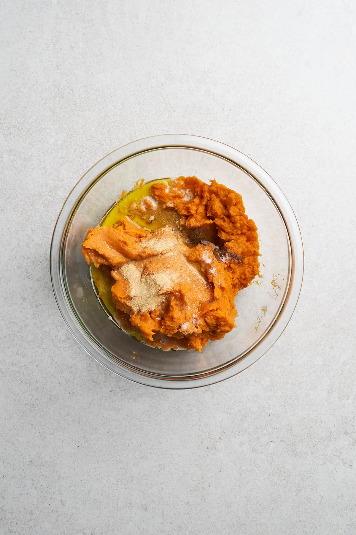 Mashed sweet potatoes with seasonings in a bowl.