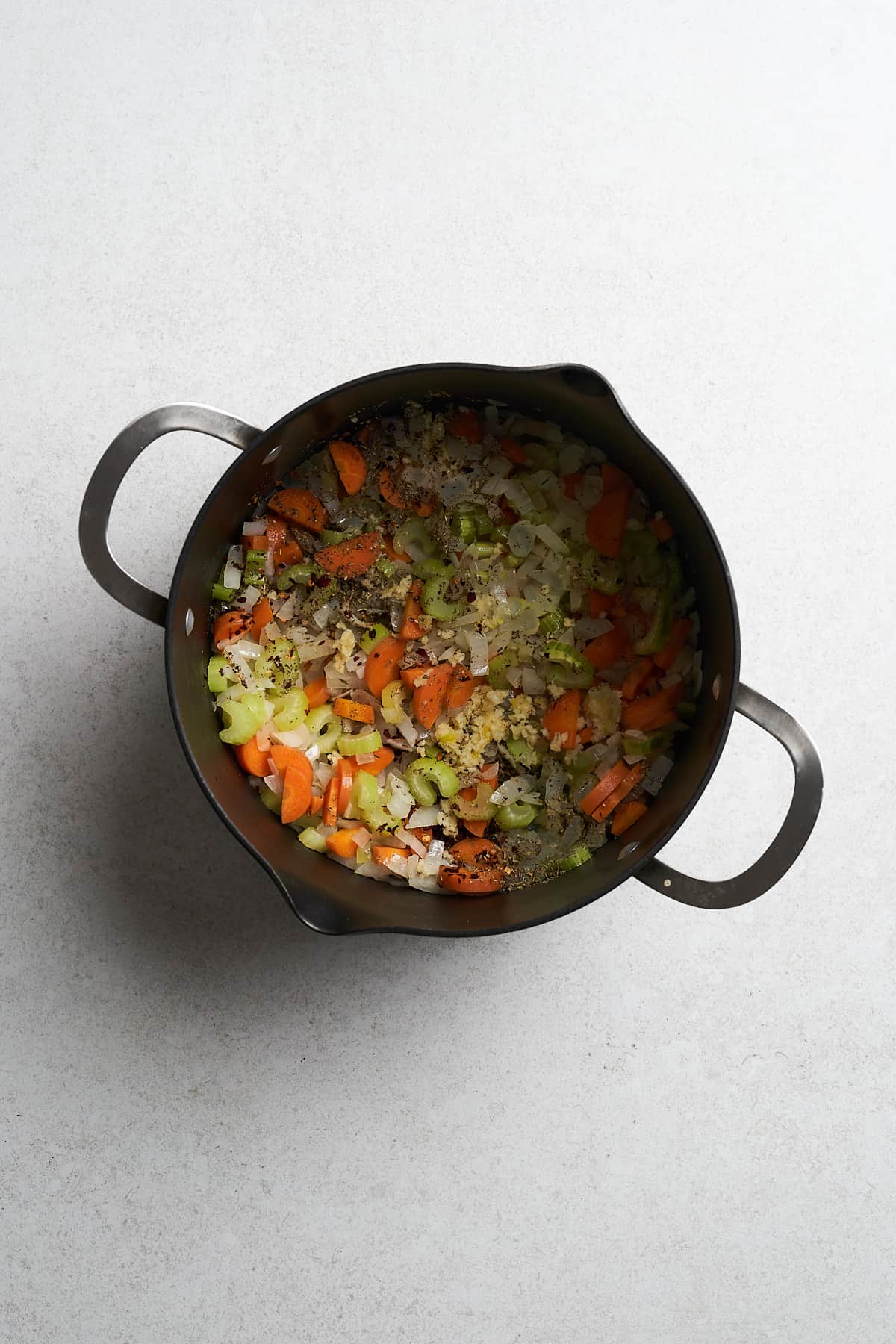 Onions, celery, carrots and seasonings in a pot.