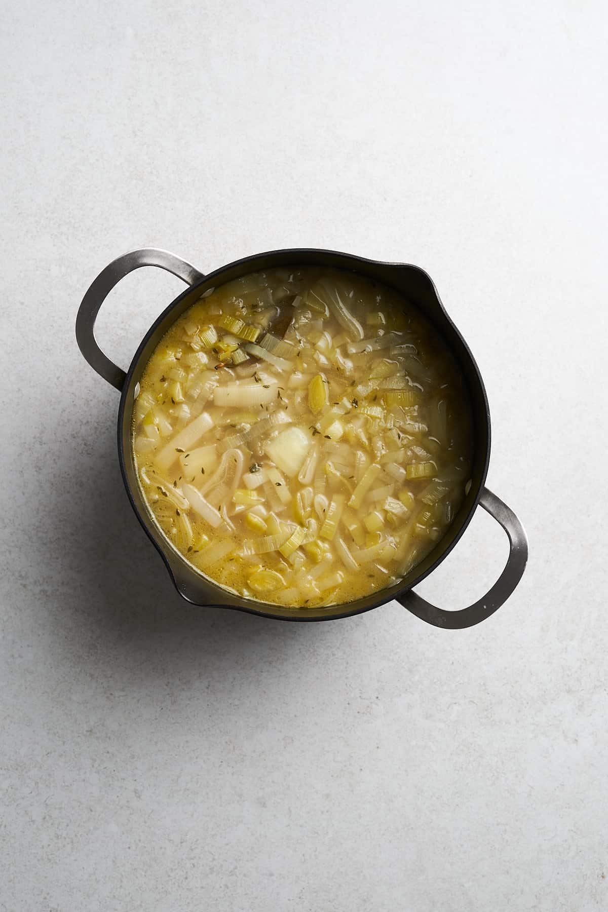 Unblended vegan potato leek soup in a pot.