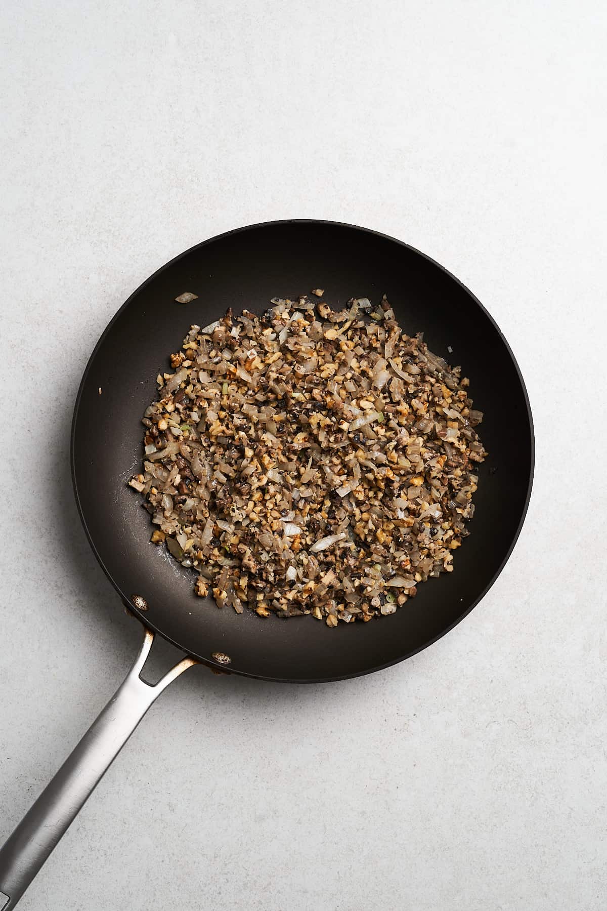 Diced onions and mushrooms in a frying pan.