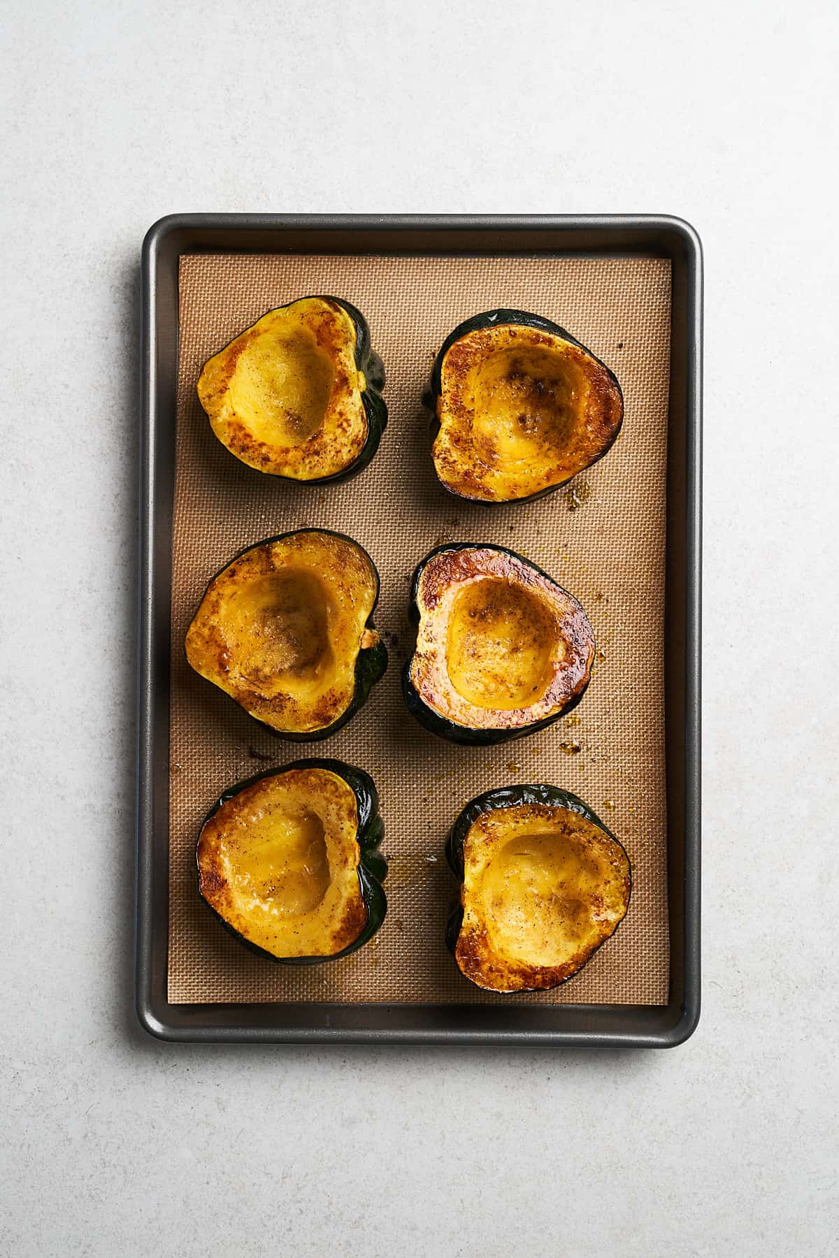 Baked acorn squash in a baking pan.