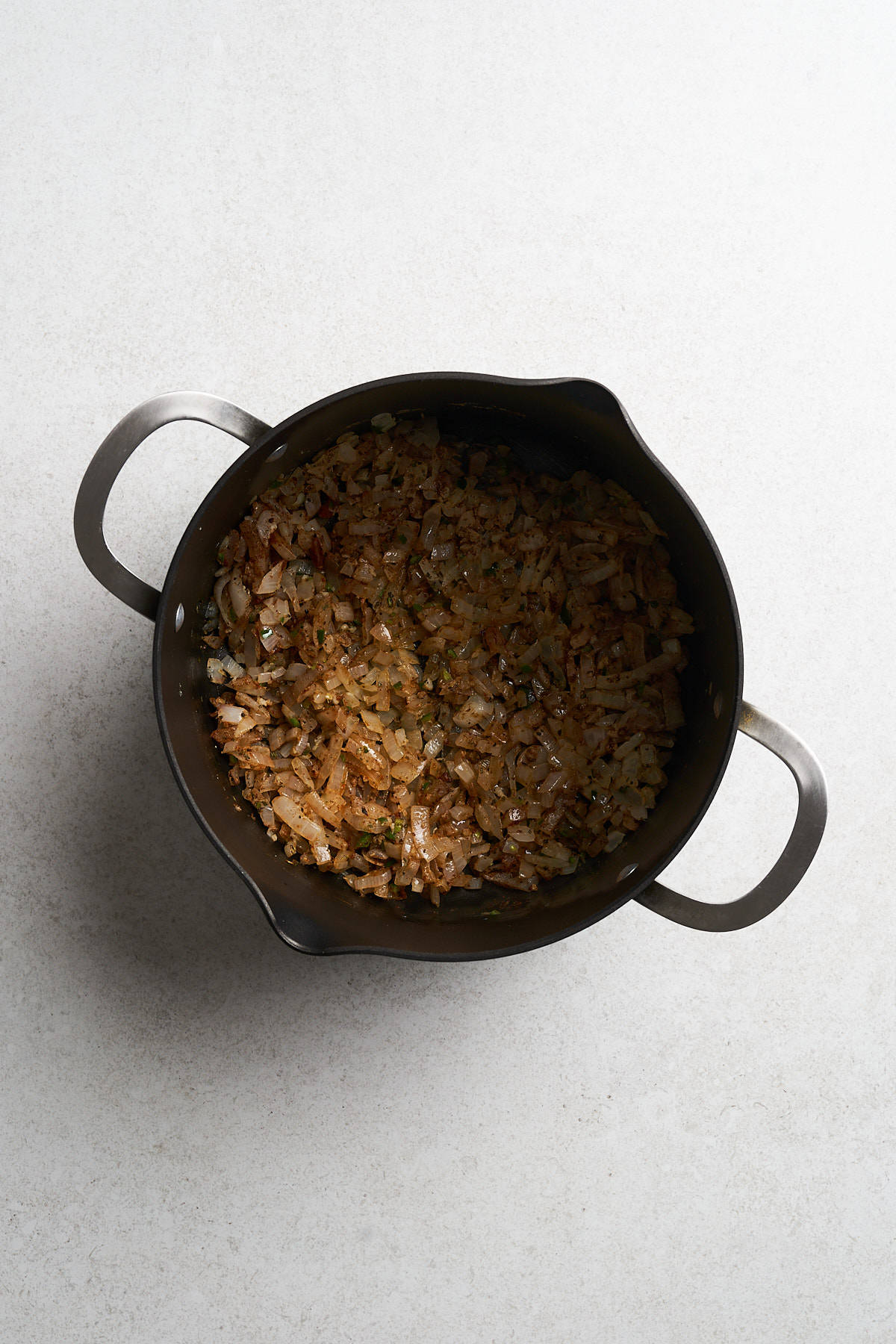 Cooked onions, garlic and chiles in a pot.