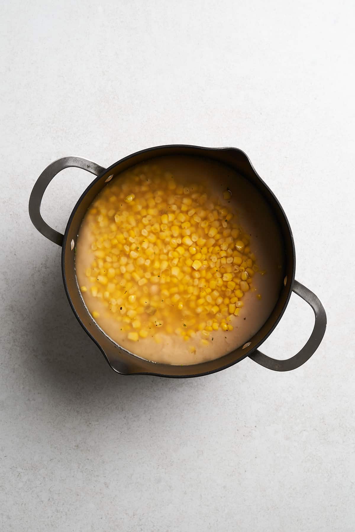 Vegetable broth, corn and spices in a pot.