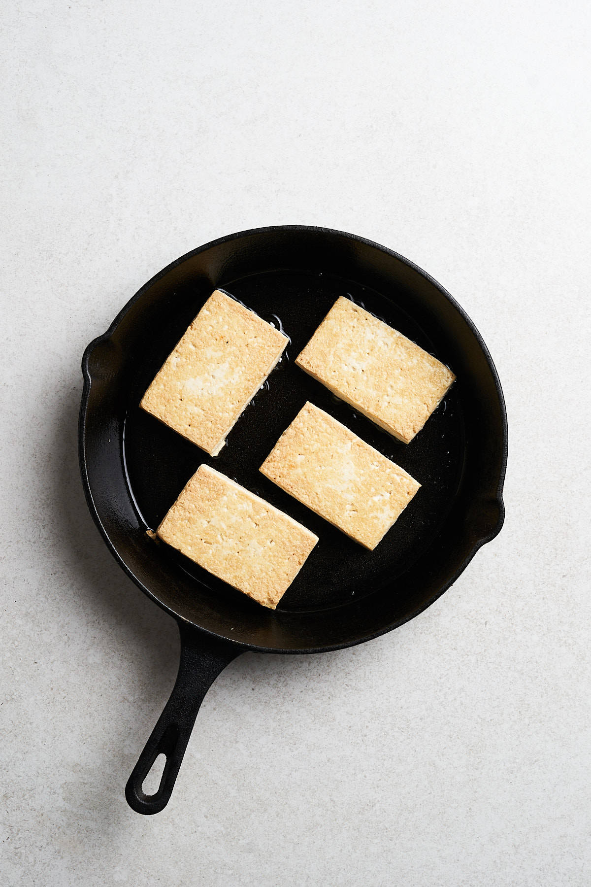Tofu slices in a frying pan.