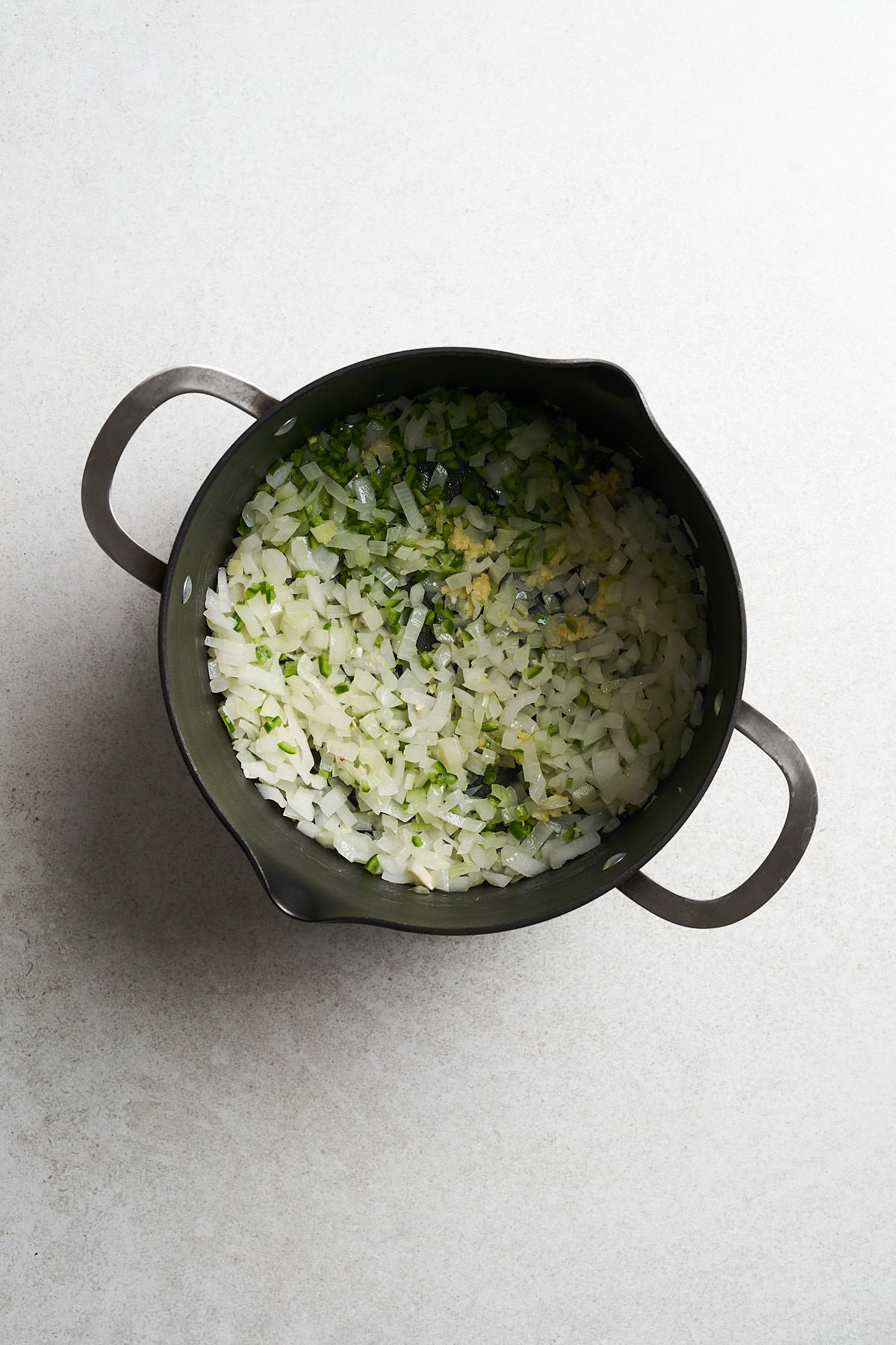 Uncooked diced onion in a saucepan.