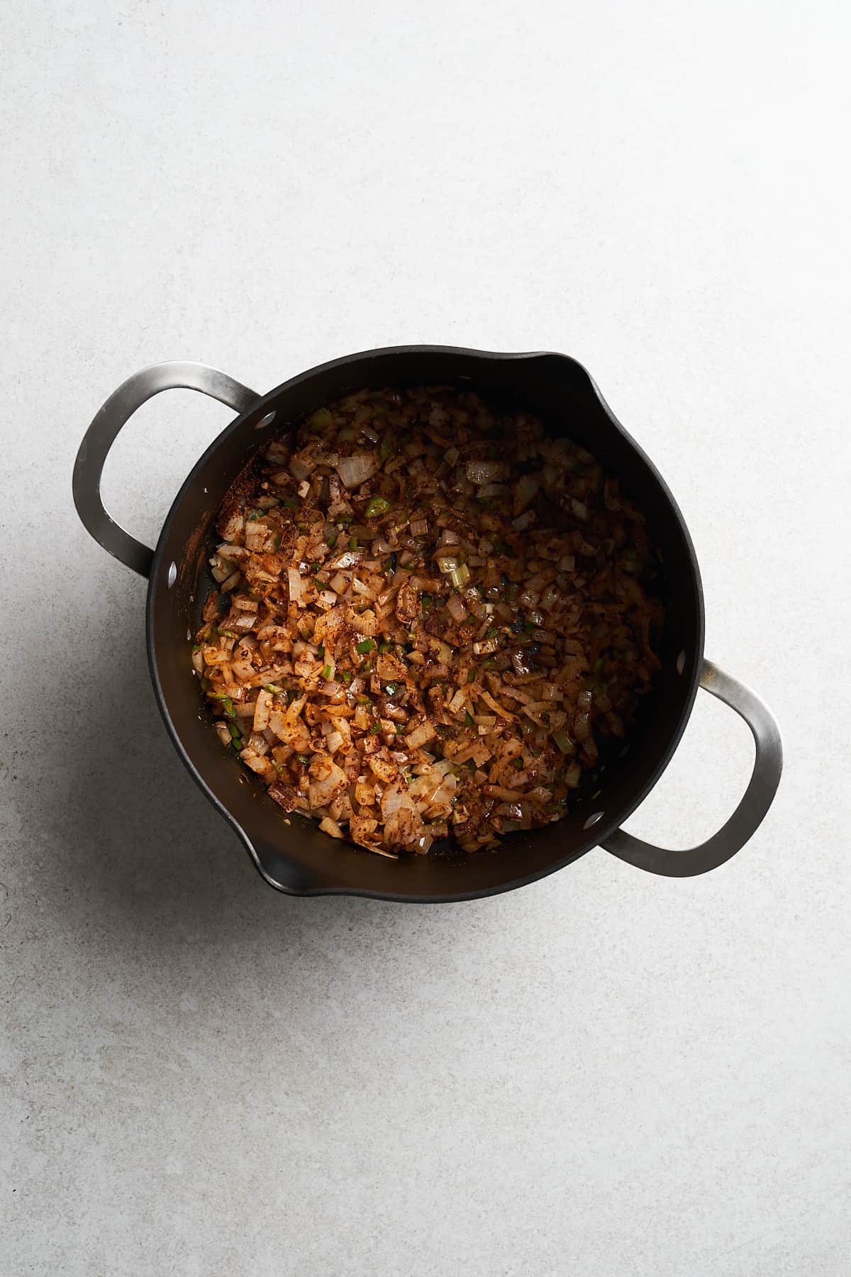 Cooked onion and spices in a saucepan.