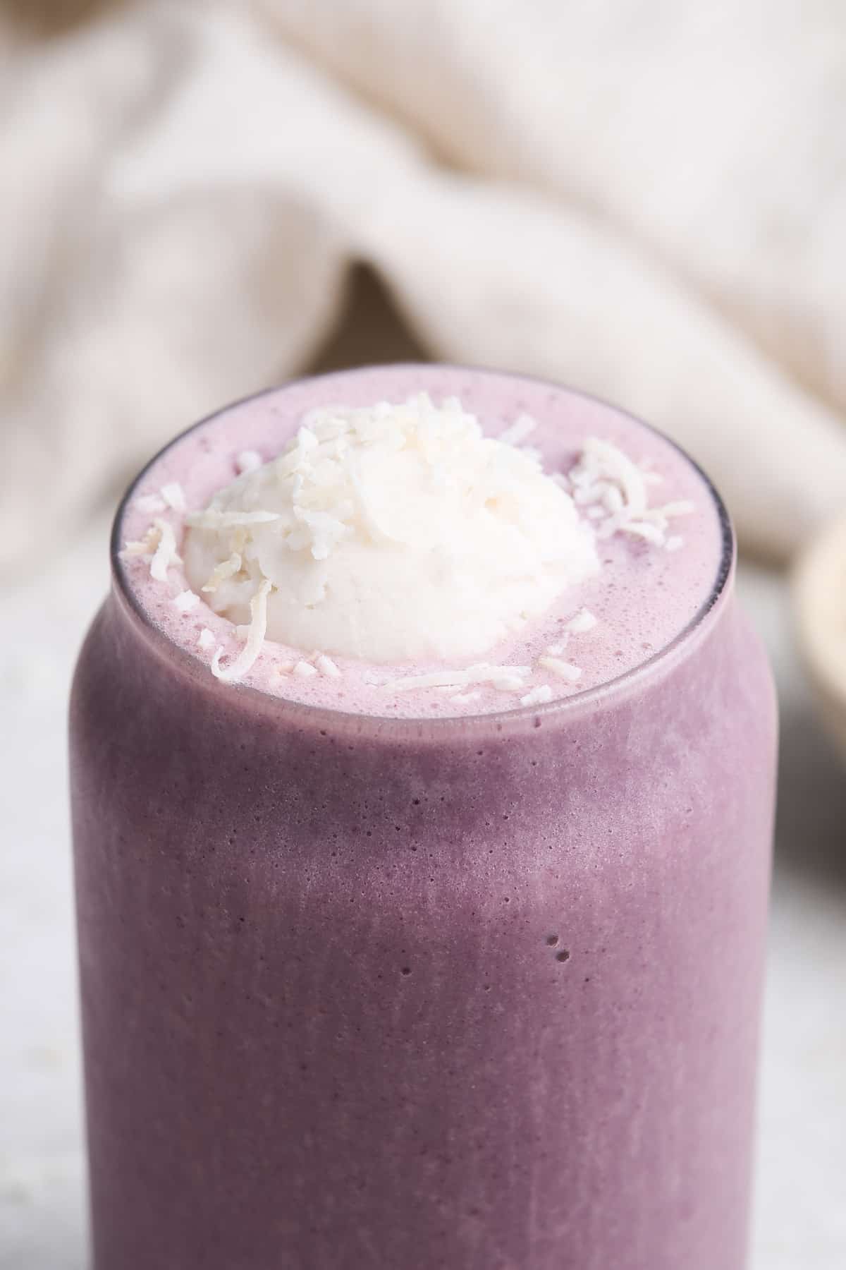 Taro smoothie in a glass with vegan whipped cream.